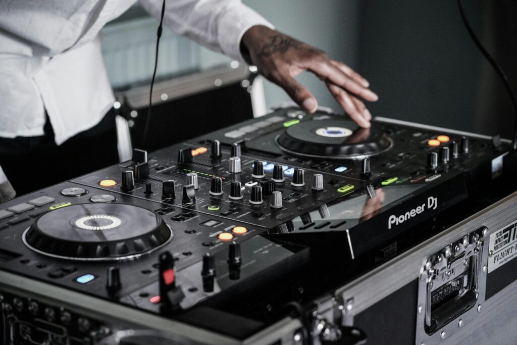 DJ's hand on a mixer with a USB stick plugged into the CDJ